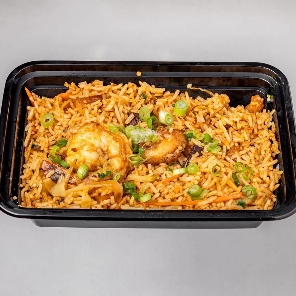 Spicy Chowk's shrimp fried rice with vegetables and green onions in a black takeout container.