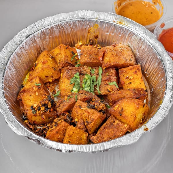 Spicy Chowk's Indian-style fried paneer cubes in a foil container, garnished with herbs and spices.