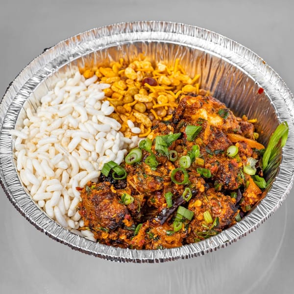 Spicy Chowk's Indian dish with puffed rice, savory mix, and chicken chili in a foil container.